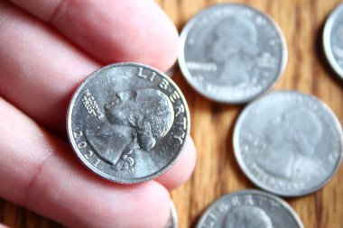 Dolar sikkeleri ve dolar banknotları tahtadan bir masaya saçılmış, düz dolar paraları..