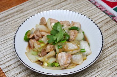 Kızarmış domuz eti ile soğan ve taze soğan karışımı beyaz tabakta servis edilen Tayland yemeği Taylandlıların yediği popüler bir yemektir..