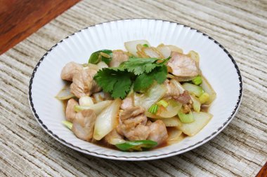 Kızarmış domuz eti ile soğan ve taze soğan karışımı beyaz tabakta servis edilen Tayland yemeği Taylandlıların yediği popüler bir yemektir..