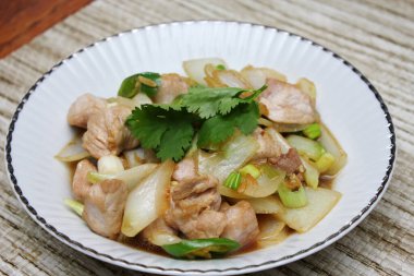 Kızarmış domuz eti ile soğan ve taze soğan karışımı beyaz tabakta servis edilen Tayland yemeği Taylandlıların yediği popüler bir yemektir..