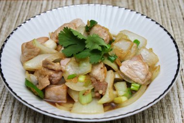 Kızarmış domuz eti ile soğan ve taze soğan karışımı beyaz tabakta servis edilen Tayland yemeği Taylandlıların yediği popüler bir yemektir..