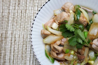 Kızarmış domuz eti ile soğan ve taze soğan karışımı beyaz tabakta servis edilen Tayland yemeği Taylandlıların yediği popüler bir yemektir..