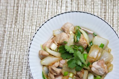 Kızarmış domuz eti ile soğan ve taze soğan karışımı beyaz tabakta servis edilen Tayland yemeği Taylandlıların yediği popüler bir yemektir..