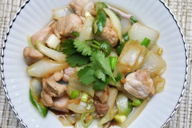 Kızarmış domuz eti ile soğan ve taze soğan karışımı beyaz tabakta servis edilen Tayland yemeği Taylandlıların yediği popüler bir yemektir..