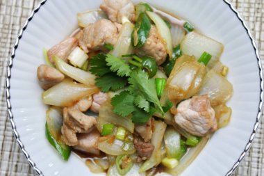 Kızarmış domuz eti ile soğan ve taze soğan karışımı beyaz tabakta servis edilen Tayland yemeği Taylandlıların yediği popüler bir yemektir..