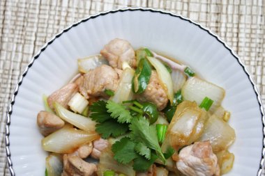 Kızarmış domuz eti ile soğan ve taze soğan karışımı beyaz tabakta servis edilen Tayland yemeği Taylandlıların yediği popüler bir yemektir..