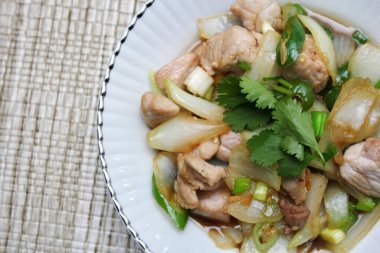 Kızarmış domuz eti ile soğan ve taze soğan karışımı beyaz tabakta servis edilen Tayland yemeği Taylandlıların yediği popüler bir yemektir..