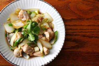 Kızarmış domuz eti ile soğan ve taze soğan karışımı beyaz tabakta servis edilen Tayland yemeği Taylandlıların yediği popüler bir yemektir..