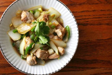 Kızarmış domuz eti ile soğan ve taze soğan karışımı beyaz tabakta servis edilen Tayland yemeği Taylandlıların yediği popüler bir yemektir..