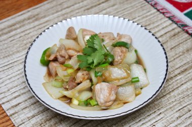 Kızarmış domuz eti ile soğan ve taze soğan karışımı beyaz tabakta servis edilen Tayland yemeği Taylandlıların yediği popüler bir yemektir..