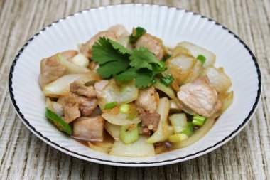 Kızarmış domuz eti ile soğan ve taze soğan karışımı beyaz tabakta servis edilen Tayland yemeği Taylandlıların yediği popüler bir yemektir..