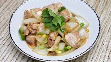 Kızarmış domuz eti ile soğan ve taze soğan karışımı beyaz tabakta servis edilen Tayland yemeği Taylandlıların yediği popüler bir yemektir..