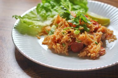 Marul ve kişniş garnitürle servis edilen bir tabakta domuz eti ve kızarmış pilav. Kızarmış pirinç Tayland 'da satılan bir sokak yiyeceğidir..