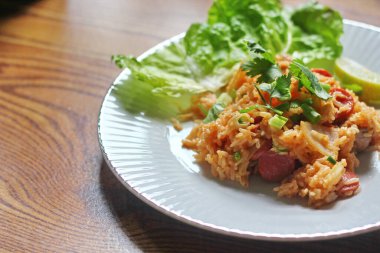 Marul ve kişniş garnitürle servis edilen bir tabakta domuz eti ve kızarmış pilav. Kızarmış pirinç Tayland 'da satılan bir sokak yiyeceğidir..