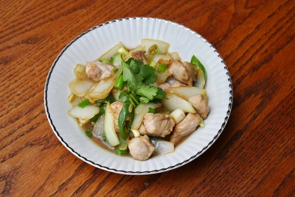 Kızarmış domuz eti ile soğan ve taze soğan karışımı beyaz tabakta servis edilen Tayland yemeği Taylandlıların yediği popüler bir yemektir..