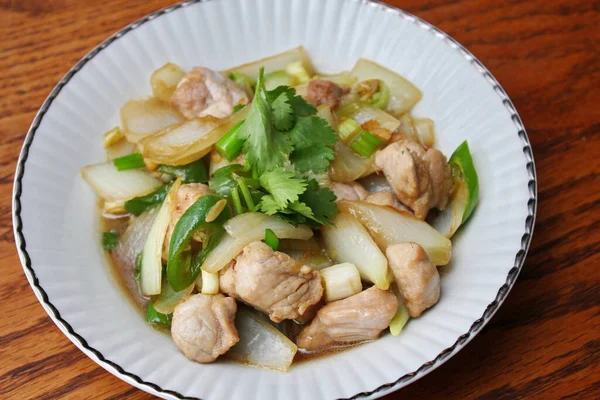 Kızarmış domuz eti ile soğan ve taze soğan karışımı beyaz tabakta servis edilen Tayland yemeği Taylandlıların yediği popüler bir yemektir..