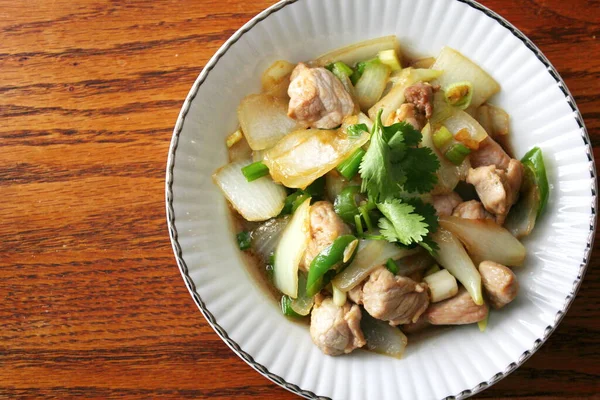 Kızarmış domuz eti ile soğan ve taze soğan karışımı beyaz tabakta servis edilen Tayland yemeği Taylandlıların yediği popüler bir yemektir..