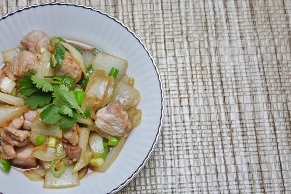 Kızarmış domuz eti ile soğan ve taze soğan karışımı beyaz tabakta servis edilen Tayland yemeği Taylandlıların yediği popüler bir yemektir..