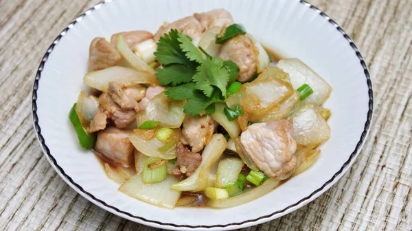 Kızarmış domuz eti ile soğan ve taze soğan karışımı beyaz tabakta servis edilen Tayland yemeği Taylandlıların yediği popüler bir yemektir..