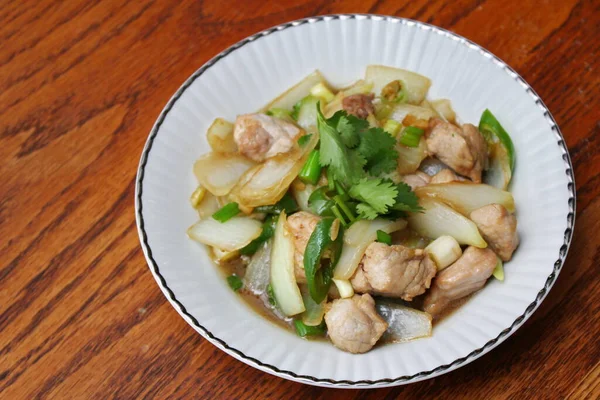 Kızarmış domuz eti ile soğan ve taze soğan karışımı beyaz tabakta servis edilen Tayland yemeği Taylandlıların yediği popüler bir yemektir..