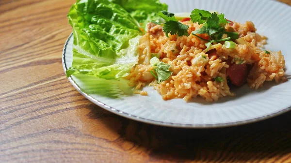 Marul ve kişniş garnitürle servis edilen bir tabakta domuz eti ve kızarmış pilav. Kızarmış pirinç Tayland 'da satılan bir sokak yiyeceğidir..