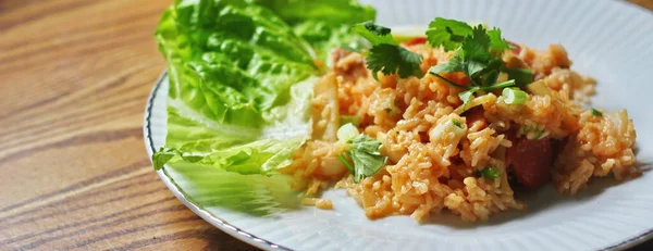 Marul ve kişniş garnitürle servis edilen bir tabakta domuz eti ve kızarmış pilav. Kızarmış pirinç Tayland 'da satılan bir sokak yiyeceğidir..