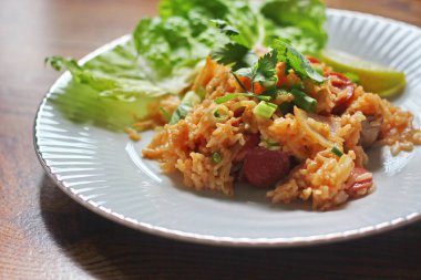 Marul ve kişniş garnitürle servis edilen bir tabakta domuz eti ve kızarmış pilav. Kızarmış pirinç Tayland 'da satılan bir sokak yiyeceğidir..