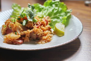 Marul ve kişniş garnitürle servis edilen bir tabakta domuz eti ve kızarmış pilav. Kızarmış pirinç Tayland 'da satılan bir sokak yiyeceğidir..