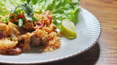 Marul ve kişniş garnitürle servis edilen bir tabakta domuz eti ve kızarmış pilav. Kızarmış pirinç Tayland 'da satılan bir sokak yiyeceğidir..