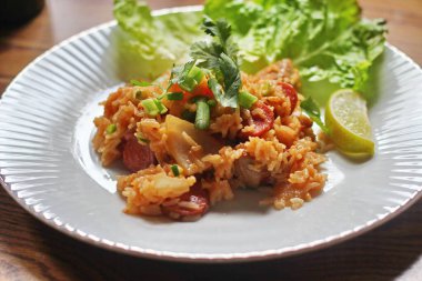 Marul ve kişniş garnitürle servis edilen bir tabakta domuz eti ve kızarmış pilav. Kızarmış pirinç Tayland 'da satılan bir sokak yiyeceğidir..