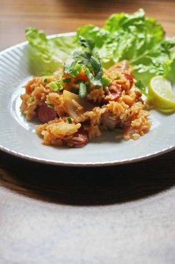 Marul ve kişniş garnitürle servis edilen bir tabakta domuz eti ve kızarmış pilav. Kızarmış pirinç Tayland 'da satılan bir sokak yiyeceğidir..