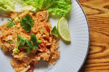 Marul ve kişniş garnitürle servis edilen bir tabakta domuz eti ve kızarmış pilav. Kızarmış pirinç Tayland 'da satılan bir sokak yiyeceğidir..