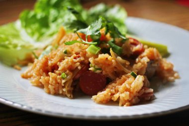 Marul ve kişniş garnitürle servis edilen bir tabakta domuz eti ve kızarmış pilav. Kızarmış pirinç Tayland 'da satılan bir sokak yiyeceğidir..