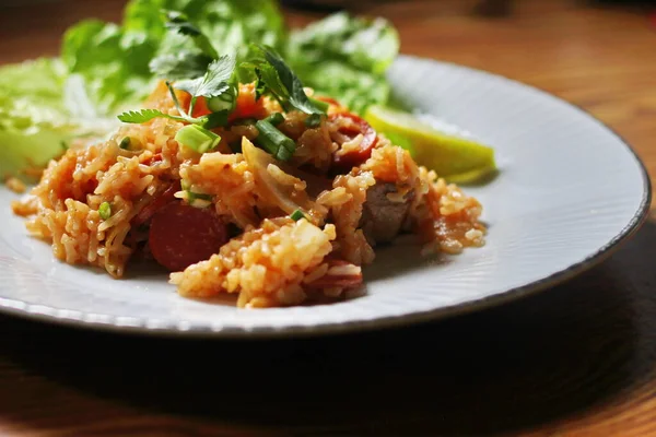Marul ve kişniş garnitürle servis edilen bir tabakta domuz eti ve kızarmış pilav. Kızarmış pirinç Tayland 'da satılan bir sokak yiyeceğidir..
