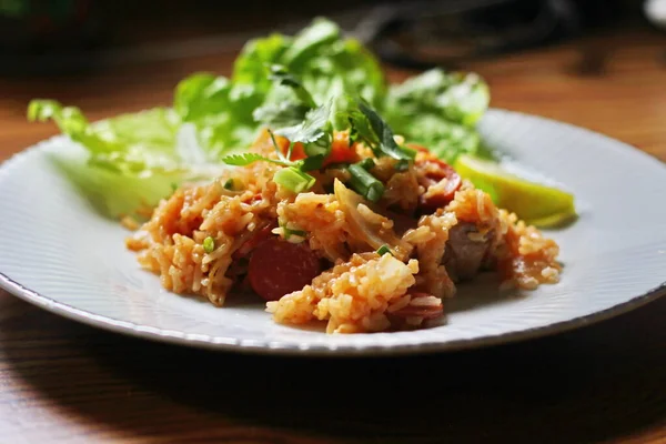 Marul ve kişniş garnitürle servis edilen bir tabakta domuz eti ve kızarmış pilav. Kızarmış pirinç Tayland 'da satılan bir sokak yiyeceğidir..