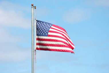 Bayrağın ucunda eski bir Amerikan bayrağı Rüzgarda dalgalanan bayrak direğinde mavi bir gökyüzü arka planında.