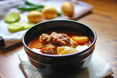 Kahverengi ahşap bir masada haşlanmış patates ve biberle servis edilen siyah tabakta servis edilen körili masaj..