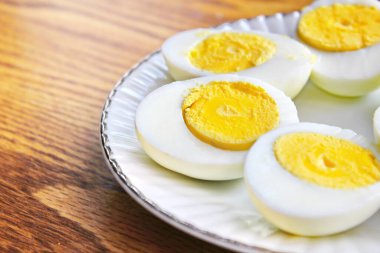 Yarım haşlanmış yumurtalar beyaz tabakta sunuldu ve ahşap bir masada servis edildi..