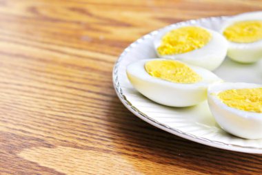 Yarım haşlanmış yumurtalar beyaz tabakta sunuldu ve ahşap bir masada servis edildi..