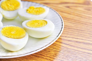 Yarım haşlanmış yumurtalar beyaz tabakta sunuldu ve ahşap bir masada servis edildi..