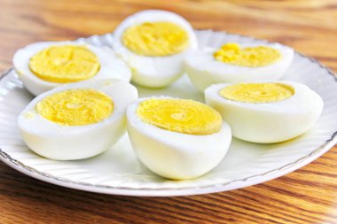 Yarım haşlanmış yumurtalar beyaz tabakta sunuldu ve ahşap bir masada servis edildi..