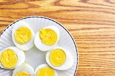 Yarım haşlanmış yumurtalar beyaz tabaklara konmuş ve ahşap bir masada servis edilmiş. Düz konum, Üst Manzara.