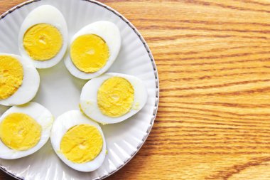 Yarım haşlanmış yumurtalar beyaz tabaklara konmuş ve ahşap bir masada servis edilmiş. Düz konum, Üst Manzara.