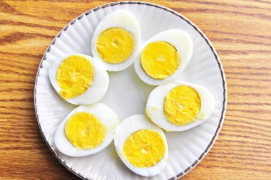 Yarım haşlanmış yumurtalar beyaz tabaklara konmuş ve ahşap bir masada servis edilmiş. Düz konum, Üst Manzara.