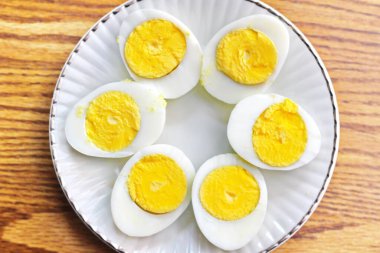 Yarım haşlanmış yumurtalar beyaz tabaklara konmuş ve ahşap bir masada servis edilmiş. Düz konum, Üst Manzara.