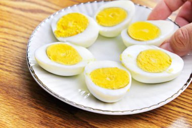 Yarım haşlanmış yumurtalar beyaz tabakta sunuldu ve ahşap bir masada servis edildi..