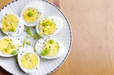 Yarısı haşlanmış yumurta, dilimlenmiş taze soğanla süslenmiş. Servise hazır beyaz bir tabakta, Düz yatıyordu, Üst Manzara.