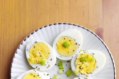 Yarısı haşlanmış yumurta, dilimlenmiş taze soğanla süslenmiş. Servise hazır beyaz bir tabakta, Düz yatıyordu, Üst Manzara.