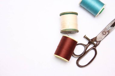 Beyaz zemine yayılmış çok renkli iplikler ve eski makas, retro makas, düz konum, kopyalama alanı.