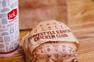 WASHINGTON, ABD - 29 HAZİRAN 2022: ABD 'deki bir kutu restoranda alkolsüz içeceklerle dolu ahşap bir masada ev usulü rance chiken kulüp burgeri.